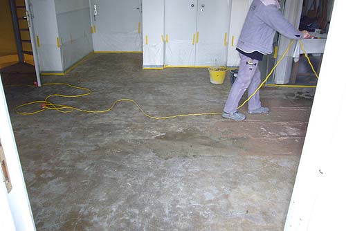 Ein Betonwerksteinboden nach Entfernen des Teppichbelags mit starken Kleberresten