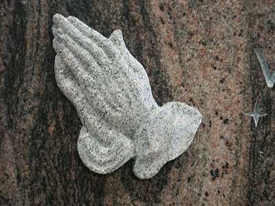 Erhaben-plastische betende Hände auf einem polierten Grabstein.