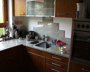 Küchenarbeitsplatte aus grauem Granit mit individueller Rückwand aus Natursteinfliesen