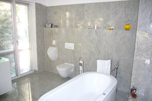 Badezimmer aus grauem Gneiss mit freistehender Badewanne