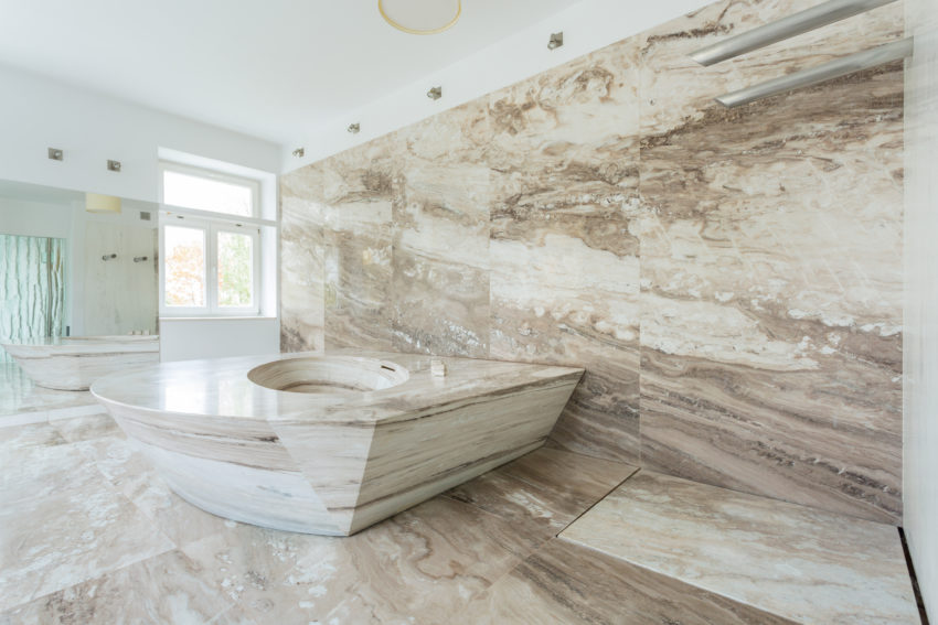 Großzügiges Badezimmer, ausgekleidet mit beigem Marmor. Highlight ist die massive marmorne Badewanne.