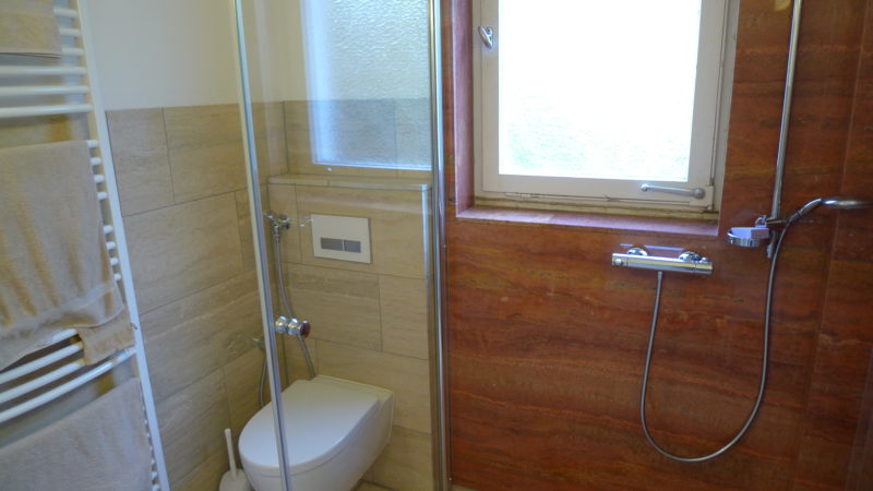 Für die Badezimmergestaltung wurden Akzente aus wunderschönem roten Travertin in Dusche und am Boden gesetzt, ergänzt von zeitlos schönem beigem Travertin.