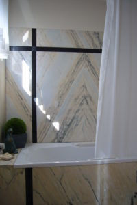 Die weiß-beigen Marmorfliesen an den Wänden des Bades wurden spiegelsymmetrisch kombiniert, schwarzer Marmor setzt Akzente.