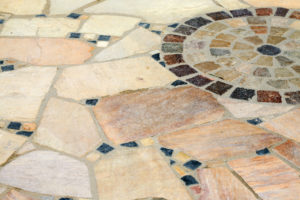 Mosaikboden aus größeren, beigen Naturstein-Polygonalplatten und bunten Mosaiksteinen