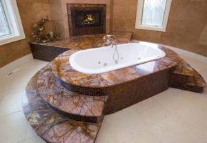 Exklusive Badewanne aus rötlichem Quarzit mit bunt schillernden Adern, dazu Mosaik in rotbraun.
