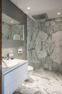 Badezimmer mit hochwertigem grau-weißen Marmor an Wänden und Boden.